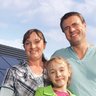Eine kleine Familie, im Hintergrund ist ein Haus mit einer Photovoltaikanlage